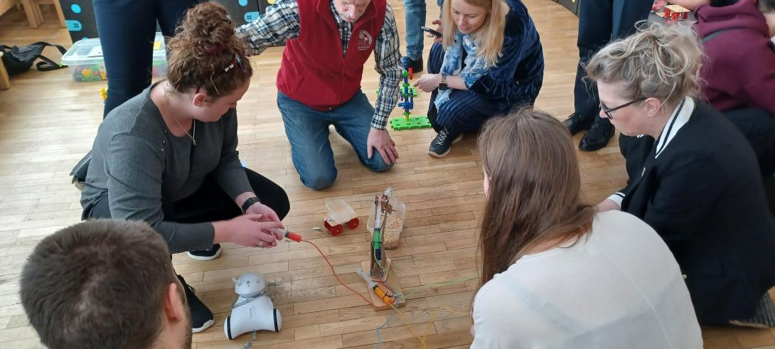 Group of People on the floor testing a robot, which sorts different kind of peas